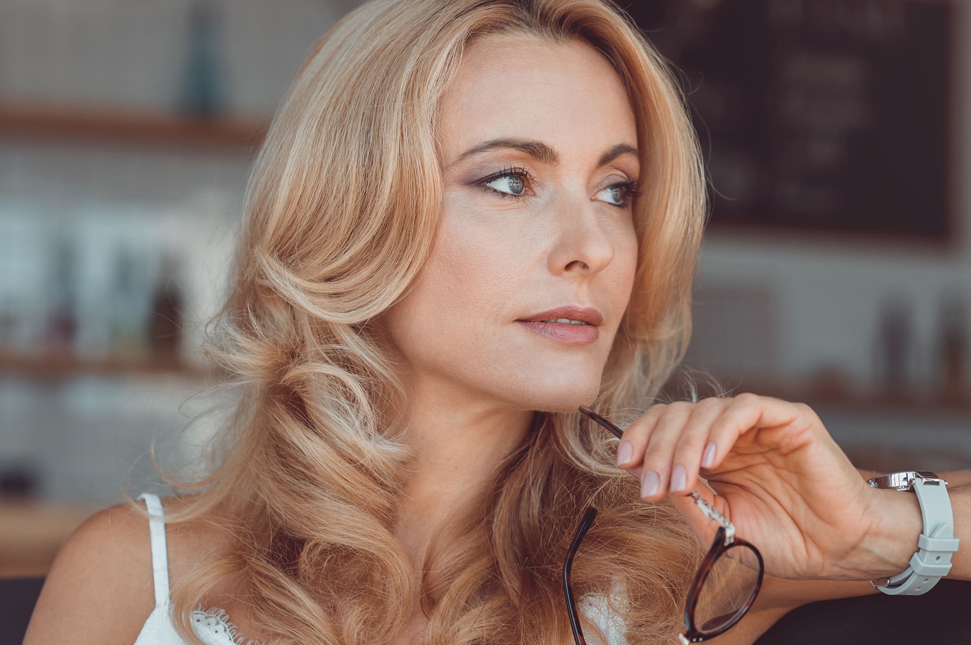 Woman looking to her left holding glasses